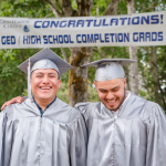 Two GED graduates smile for a photo outside of the commencement ceremony