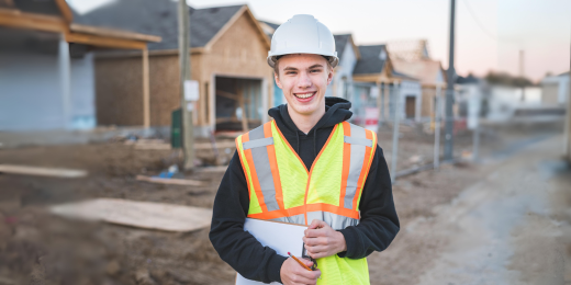 Construction student standing in front of new home construction