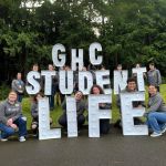 members of GHC's student life team pose for a photo holding letters that spell out GHC Student Life