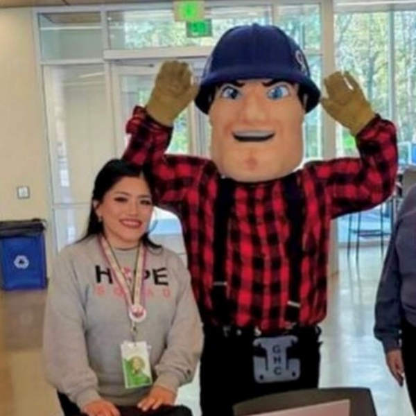 Cari sits nect to a standing Charlie Choker in one of GHC's common areas. They both smile for the Camera. 