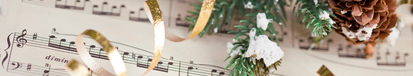 Sheet music with ribbon pine needles and pine cone on top